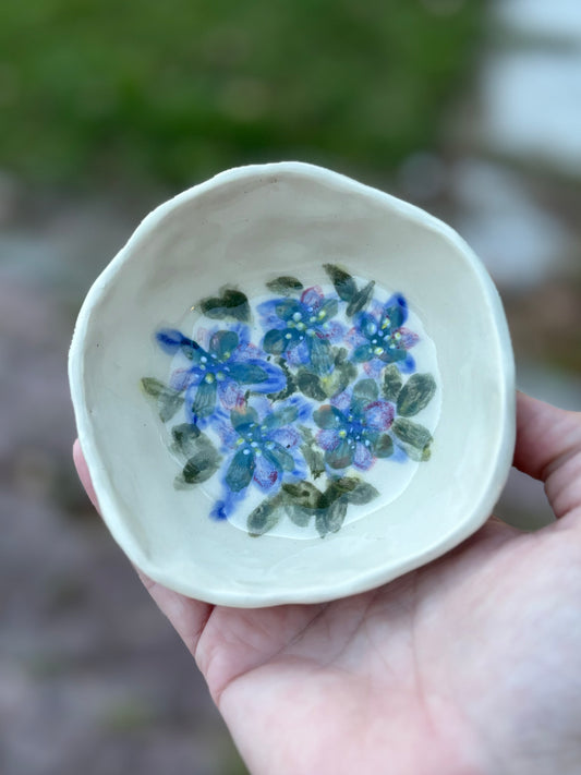 Photo of a white ceramic dish with painted purple flowers inside.