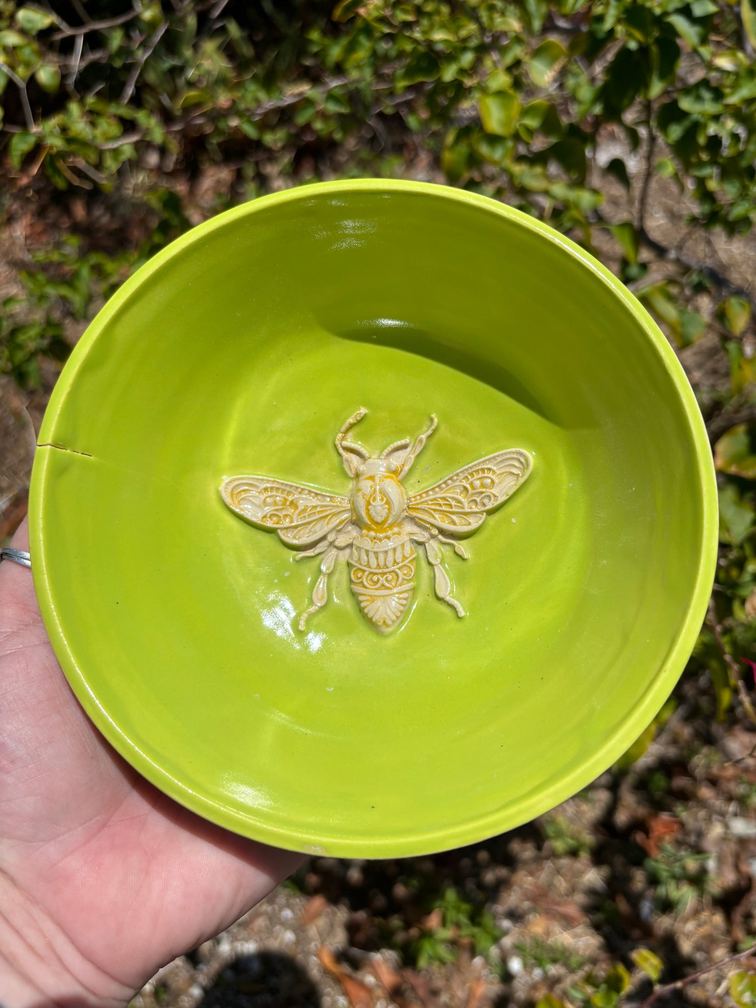 Photo of a bright green bowl with a beautiful clay bumblebee with yellow accents in the bottom.