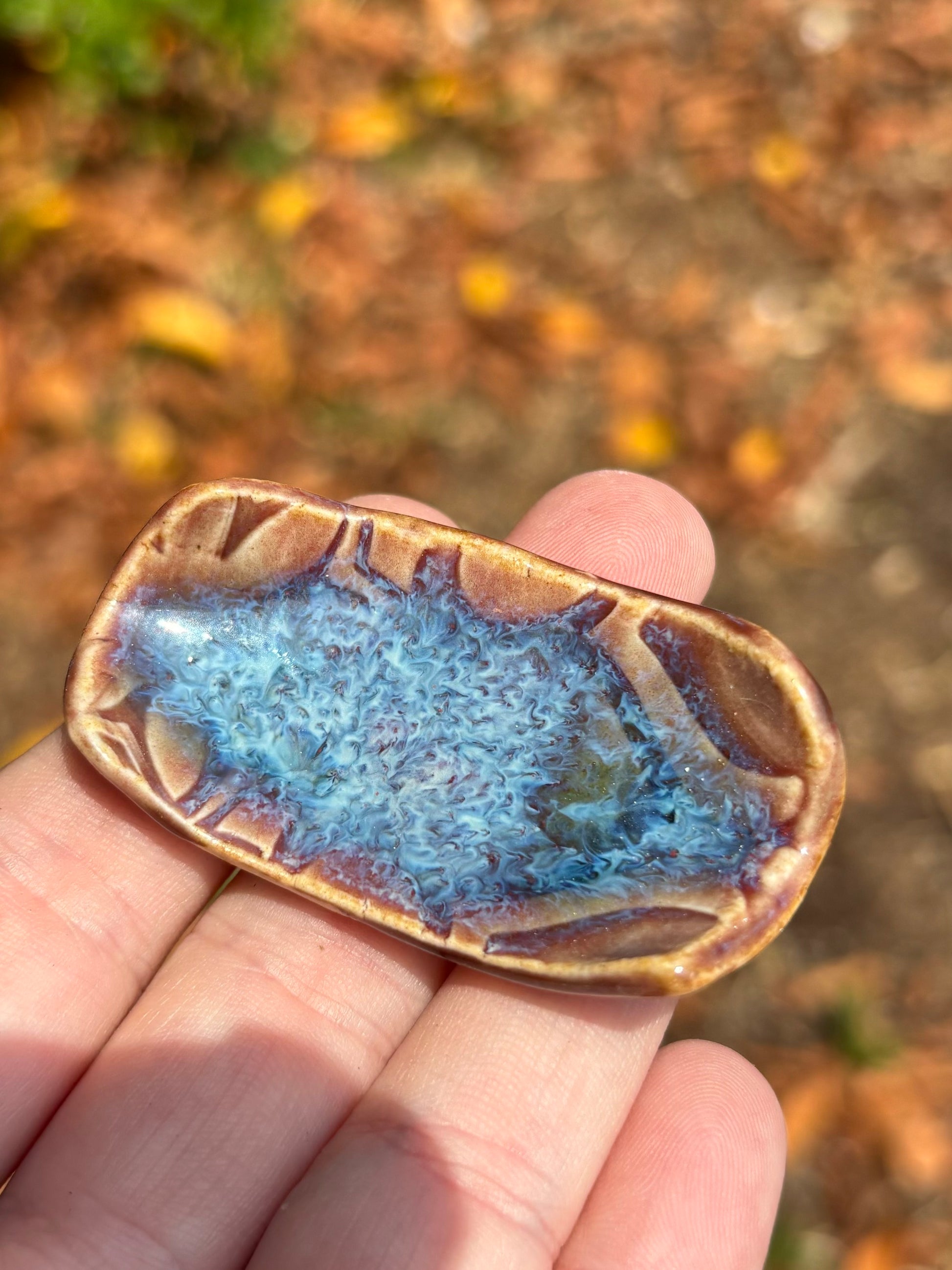 Photo of a small ceramic chopstick rest with a brilliant blue nebula of glaze.