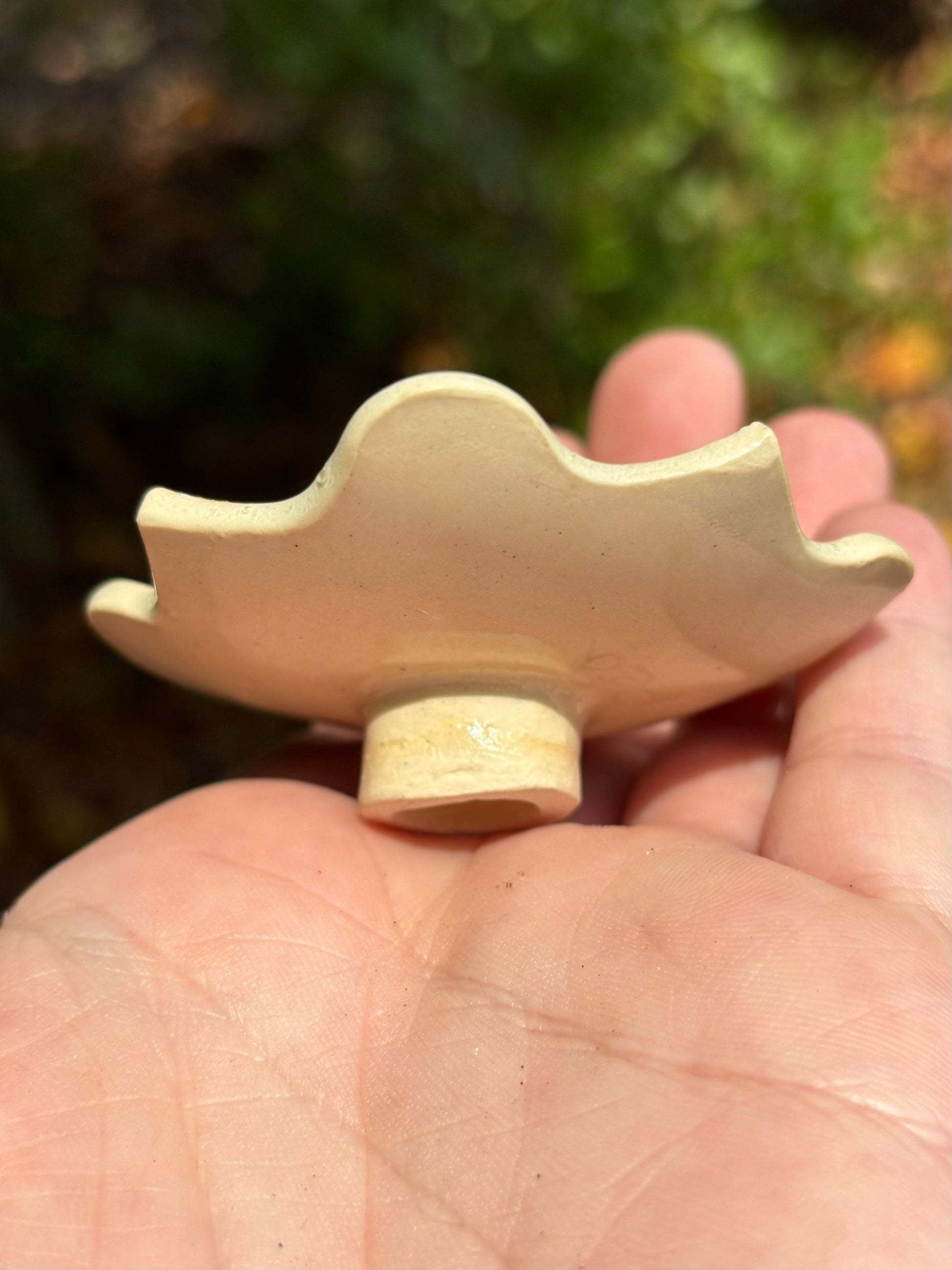 side view of a small ceramic dish with a tall foot.