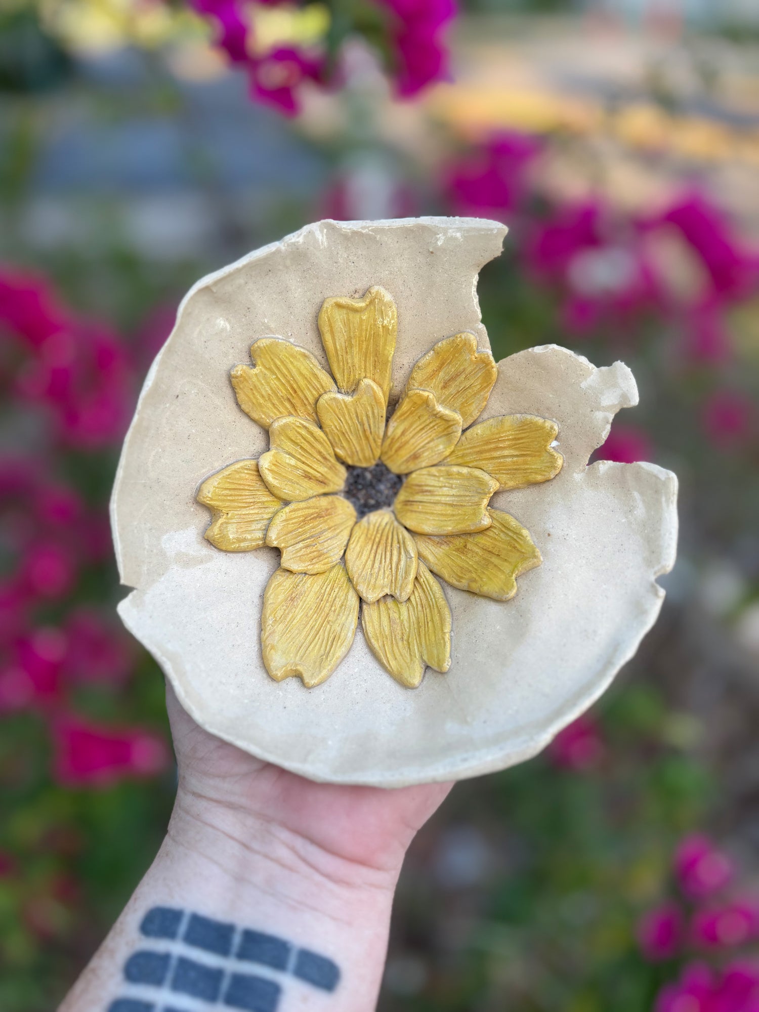 Photo of a sculptural bowl with a torn edge.  A texutred yellow sunflower lines the inside of the bowl.  