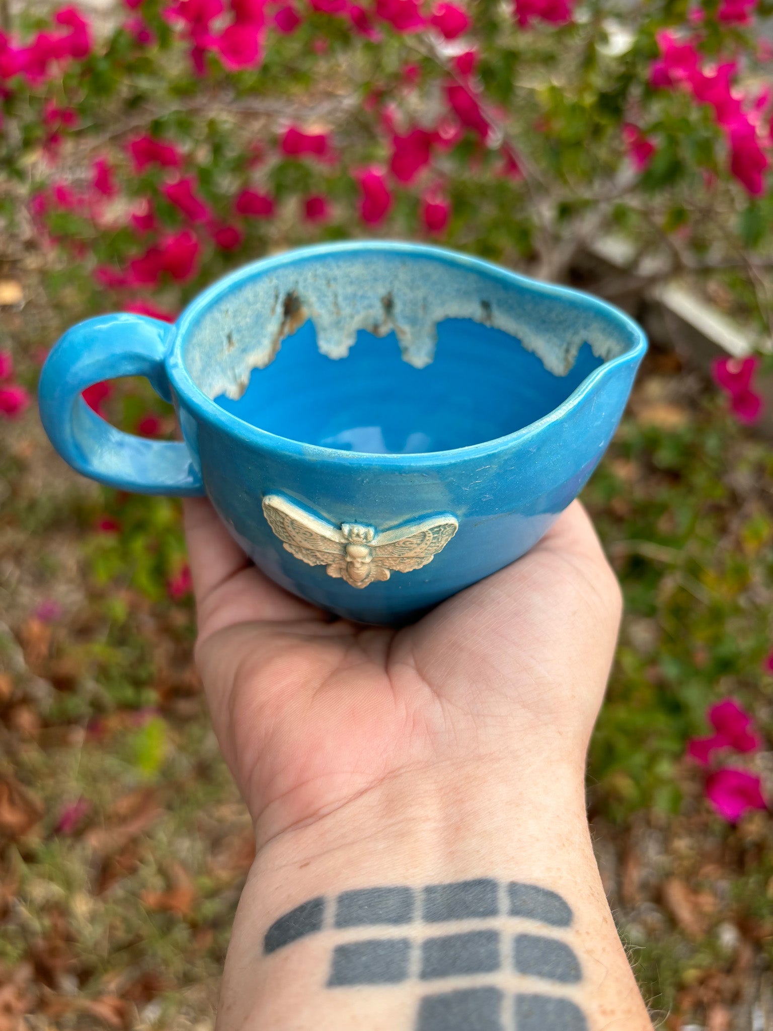 Photo of a bright blue creamer with a cicada on the side.