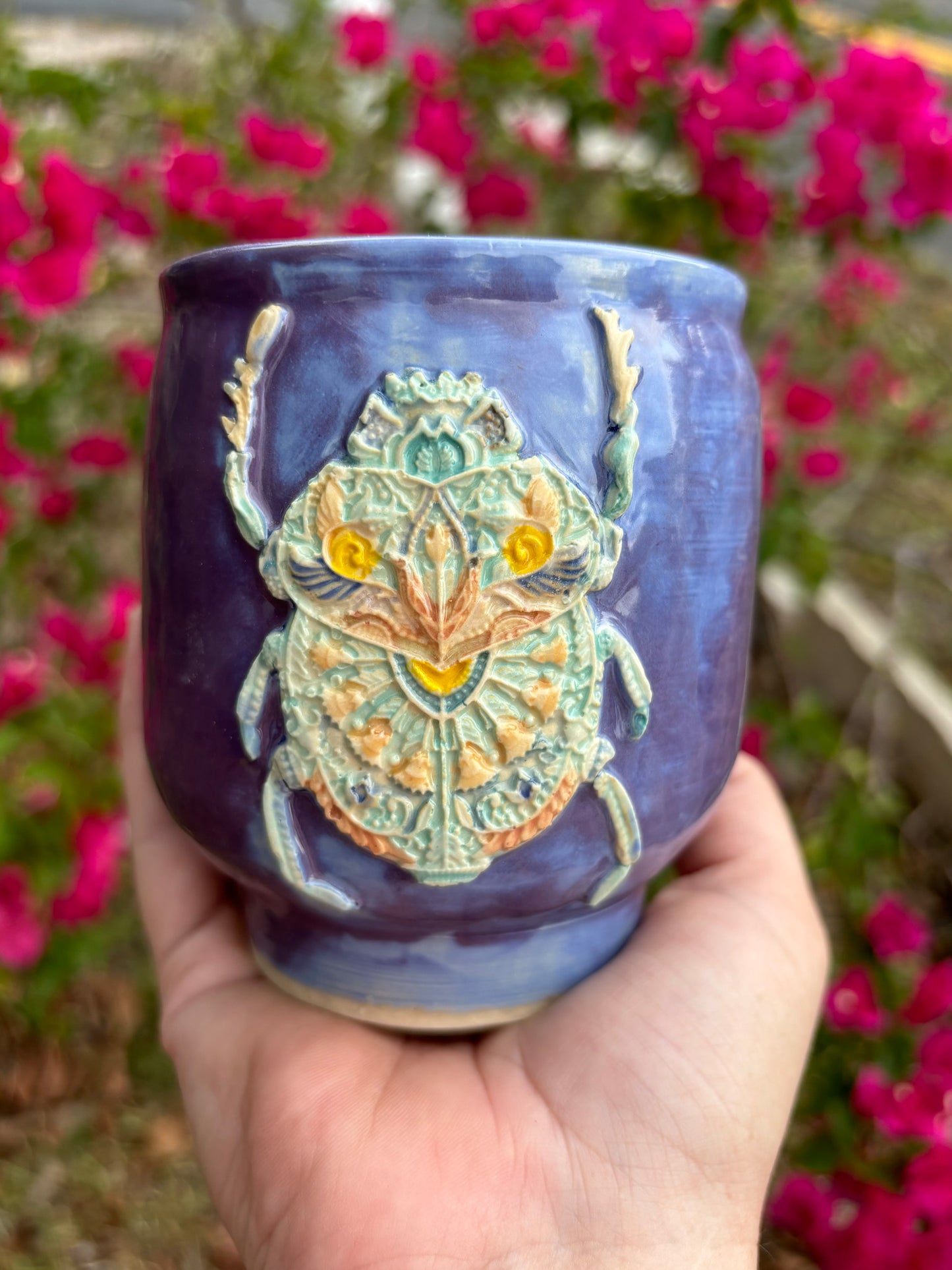 Photo of a large purple mug with an ornate scarab beetle adorning the side.  The scarab is brightly painted like it's covered in jewels.