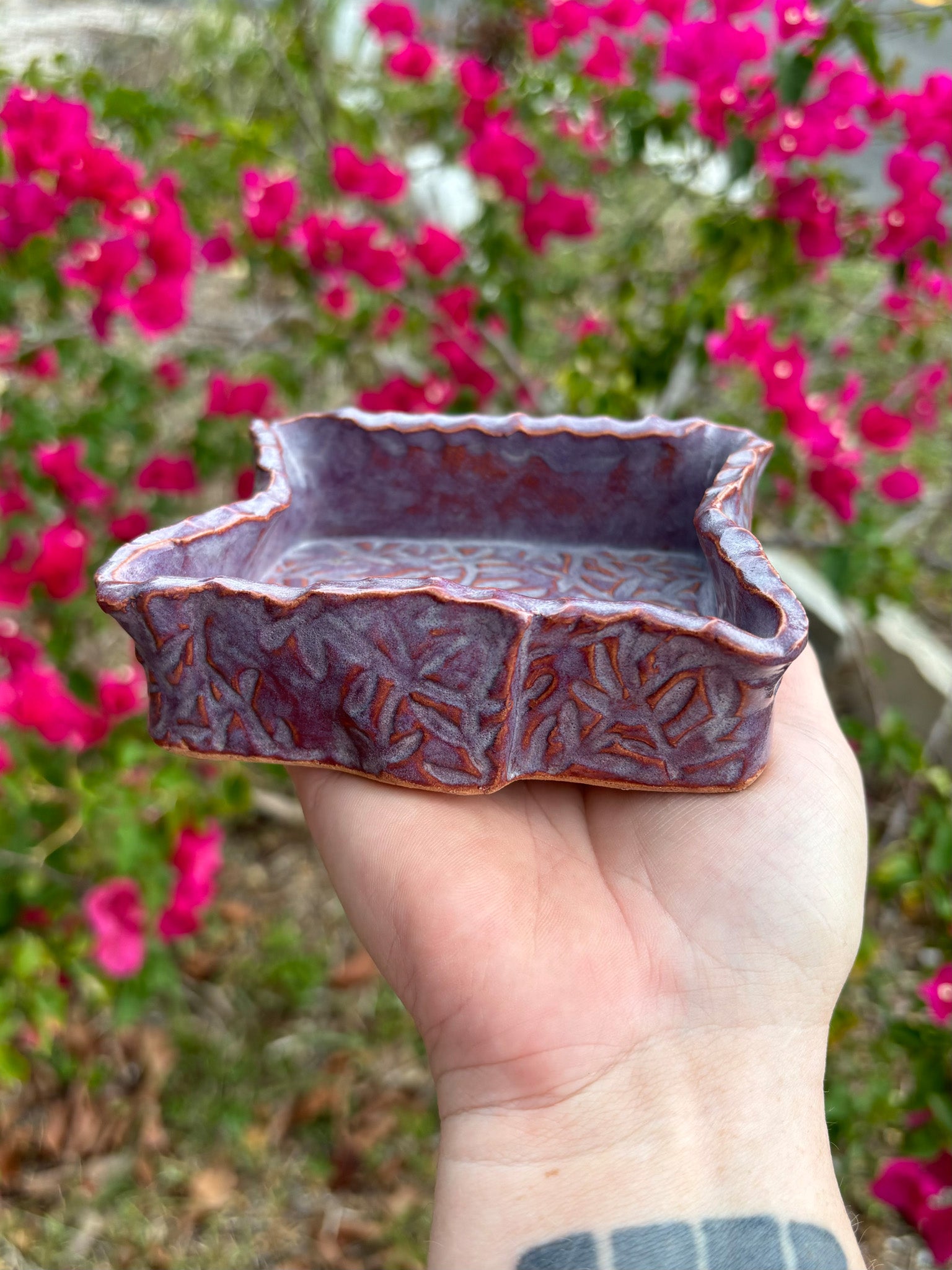 Side view of a purple ceramic box with leafy vines imprinted into the clay.