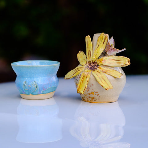 Photo of a small blue ceramic vase and a sculptural sunflower vase.