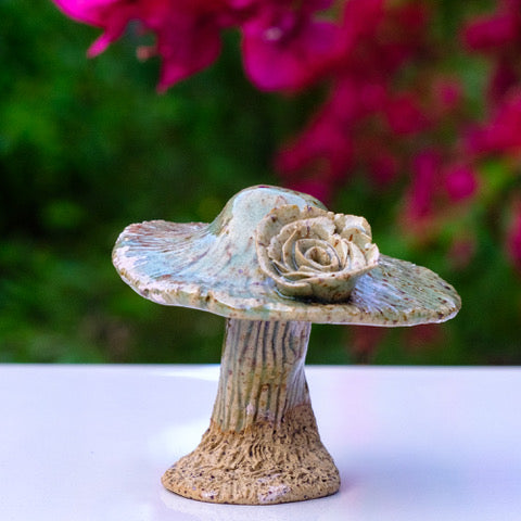 Photo of a small sculptural ceramic mushroom with a clay rose on top.
